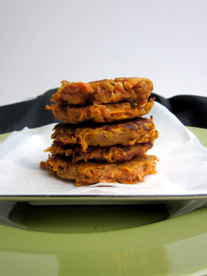 A stack of five sweet potato fritters on a white plate.