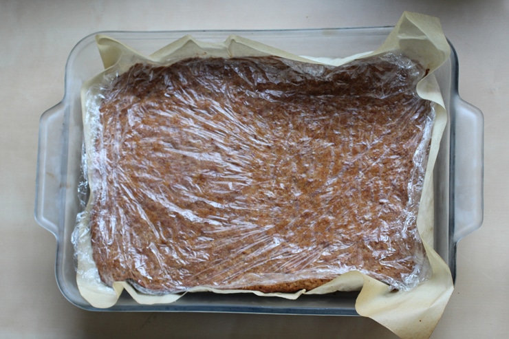 A 9x13 glass pan filled with cake and covered in plastic wrap.