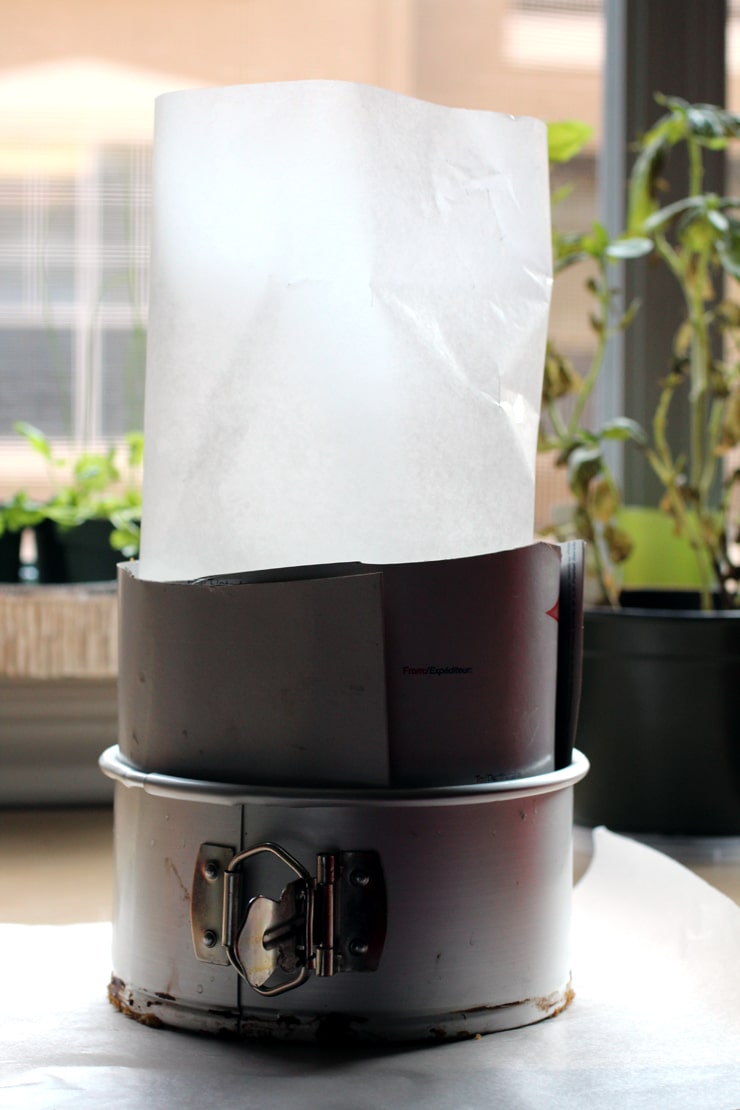 A six inch springform cake pan with cardboard and parchment paper placed inside it as a guide.