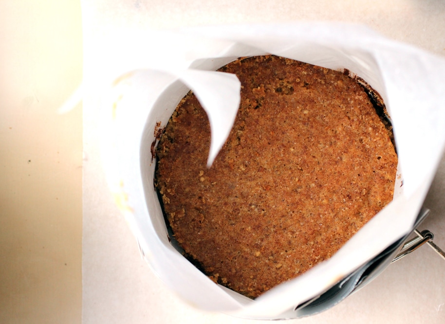 A cake pan lined with parchment paper topped with a layer of cake.