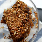 Three quarters of a pretzel layer cake on a glass cake stand.