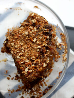 Three quarters of a pretzel layer cake on a glass cake stand.