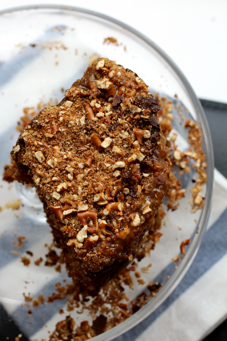 Three quarters of a pretzel layer cake on a glass cake stand.