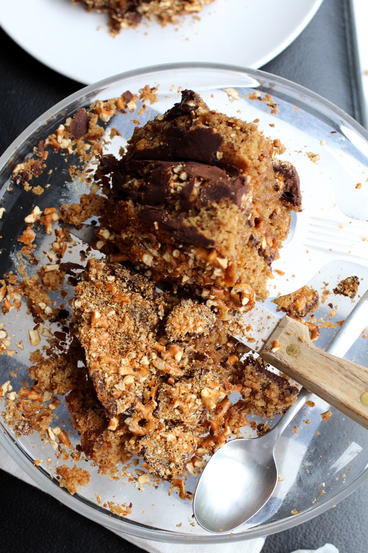 The remainder of a pretzel layer cake being sliced on a glass cake plate.