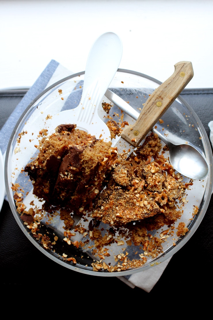 A slice of pretzel cake on a glass cake stand with a knife.