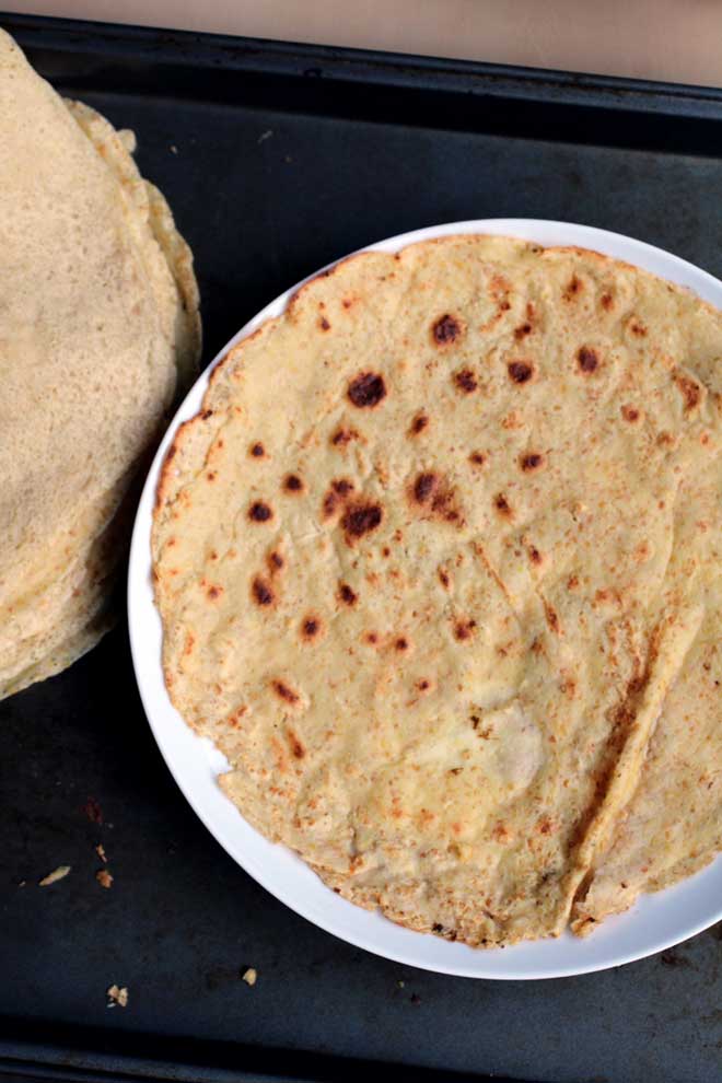 A speckled tortilla made out of chickpea flour on a white plate.