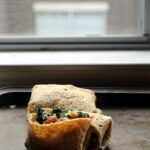 A gluten free tortilla filled with vegetables on a baking sheet.