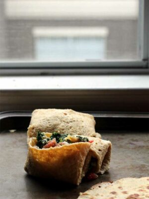 A gluten free tortilla filled with vegetables on a baking sheet.