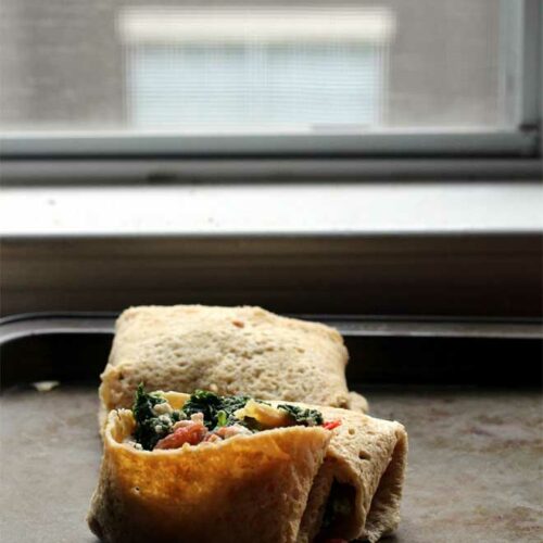 A gluten free tortilla filled with vegetables on a baking sheet.