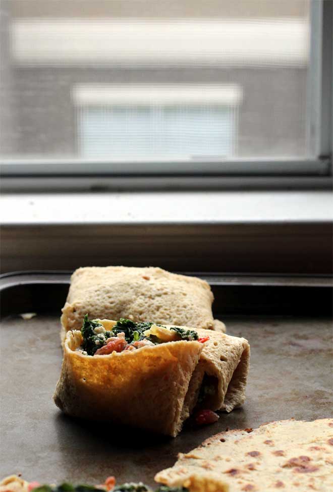 A gluten free tortilla filled with vegetables on a baking sheet.