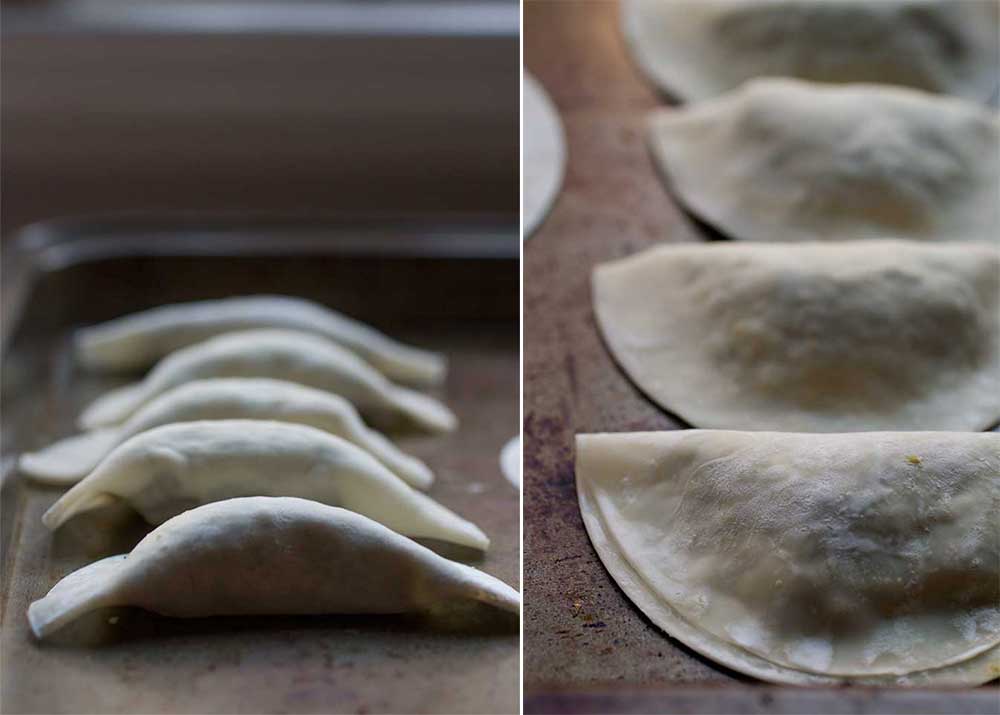 Assembled kale and tofu dumplings on a metal sheet.