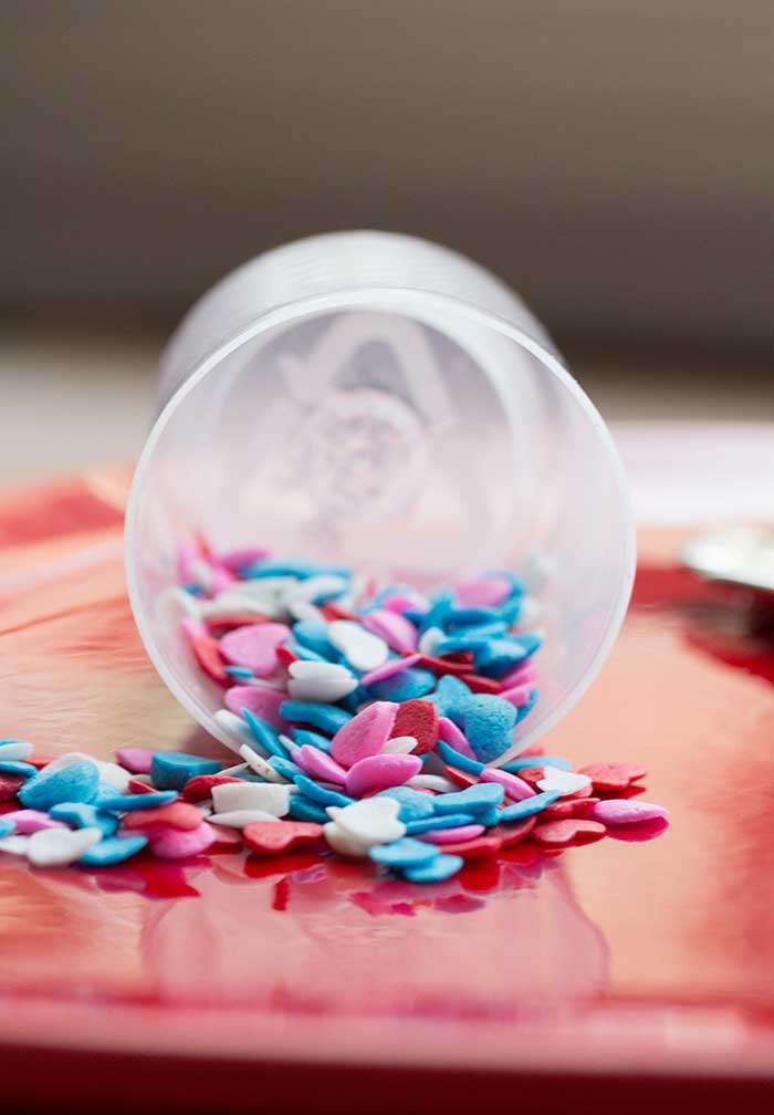 Close up on sprinkles trickling out of a sprinkles container.