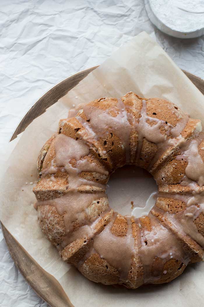 Frosted apple bundt cake on a parchment-lined platter.