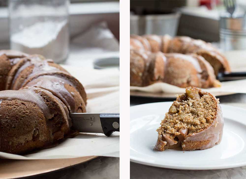 A knife cutting into a bundt cake next to a slice of apple cake on a white plate.