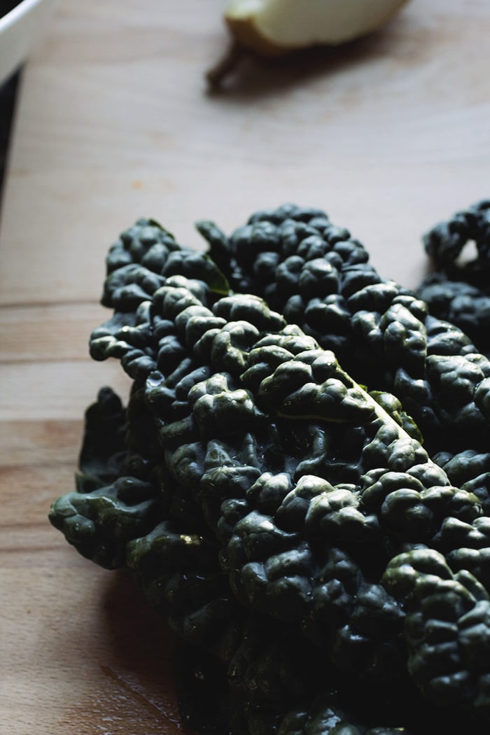 A pile of dinosaur kale on a wooden table.