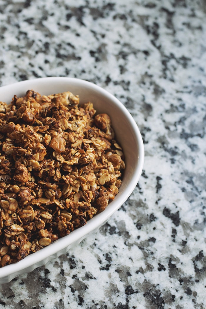granola in white bowl on a marble countertop.