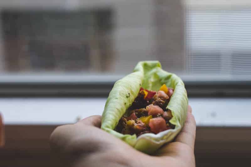 Cabbage wraps filled with chickpea taco meat on a hand.