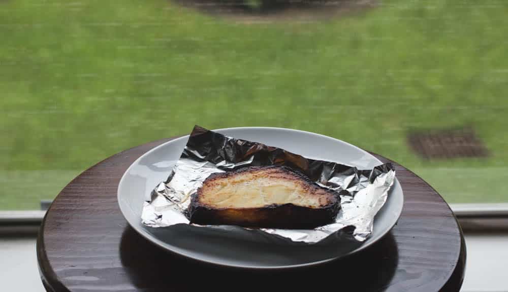 Miso glazed cod on a piece of foil on a white plate.