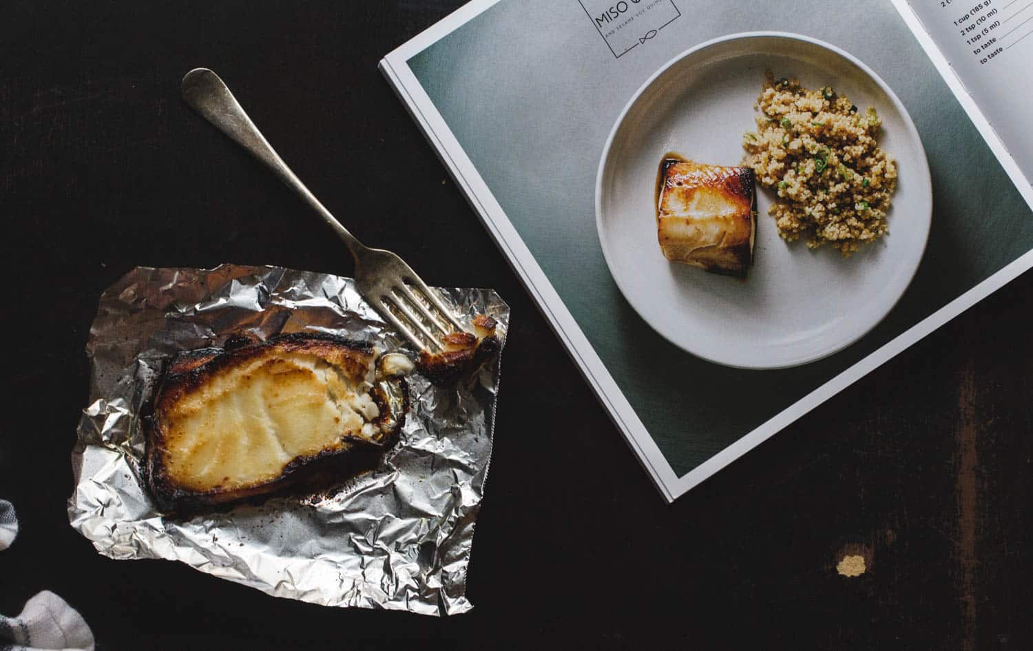 Easy Gourmet cookbook opened to the miso-glazed cod page next to a piece of miso glazed cod on a piece of foil.