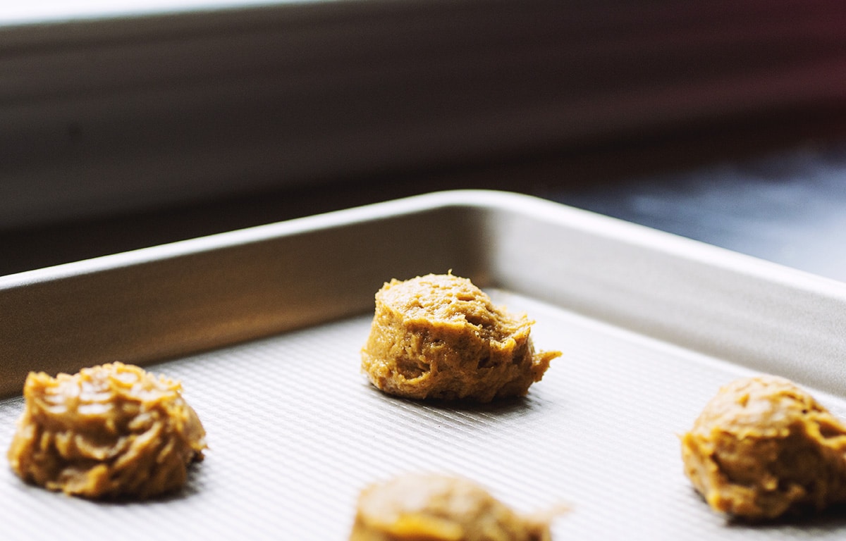 A ball of pumpkin cookie dough on a metal cookie sheet.