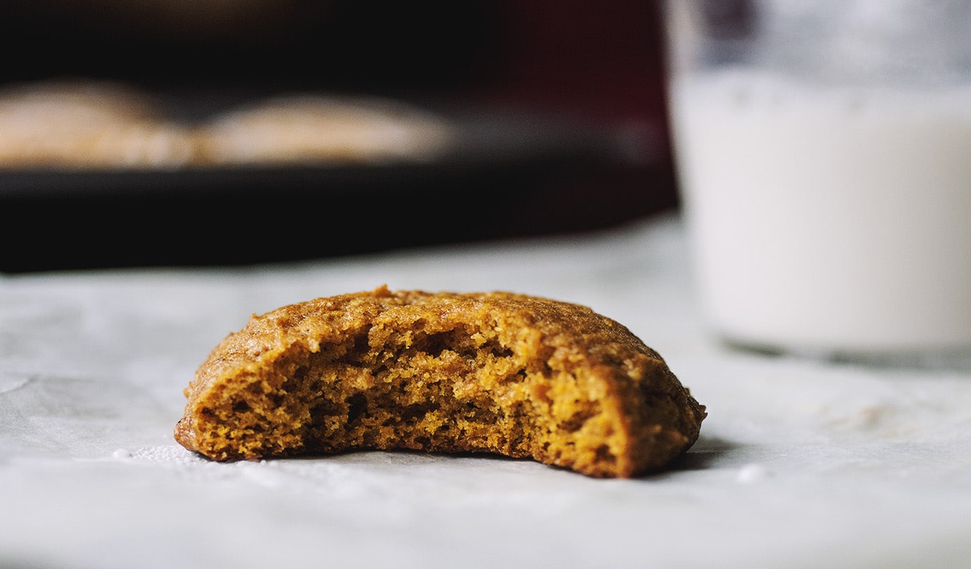 Close up on a pumpkin cookie with a bite taken out of it to show the fluffy texxture.