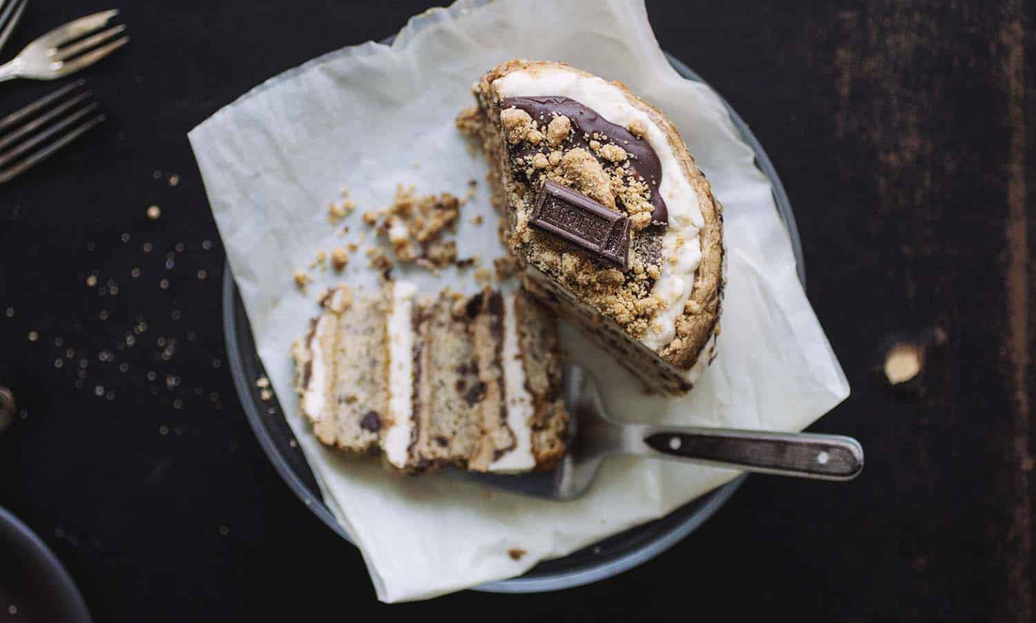 A s\'mores layer cake with a cake serving utensil holding a slice.