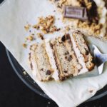 A slice of s'mores cake layered with marshmallow fluff, graham frosting and chocolate ganache on a black plate.