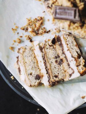 A slice of s'mores cake layered with marshmallow fluff, graham frosting and chocolate ganache on a black plate.