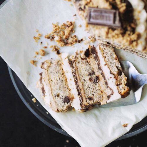 A slice of s'mores cake layered with marshmallow fluff, graham frosting and chocolate ganache on a black plate.