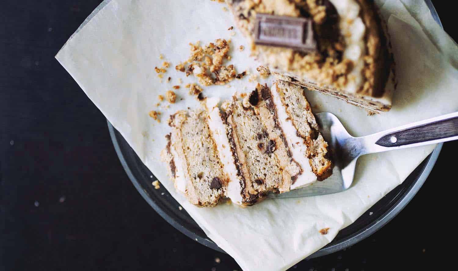 A slice of s\'mores cake layered with marshmallow fluff, graham frosting and chocolate ganache on a black plate.