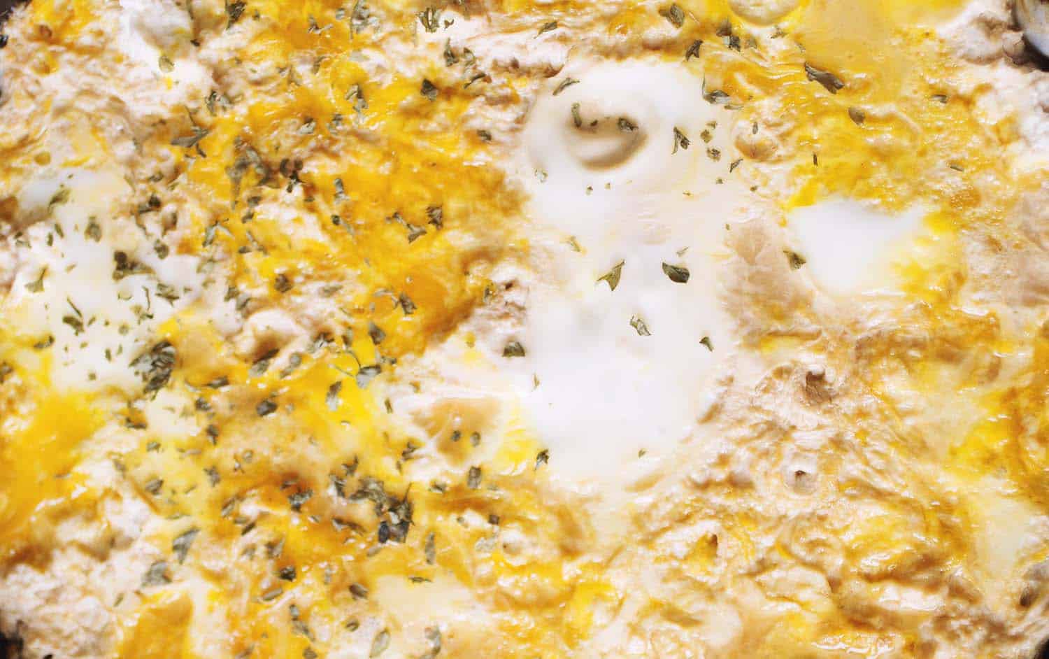 A close up on eggs swirled with tofu and onions.