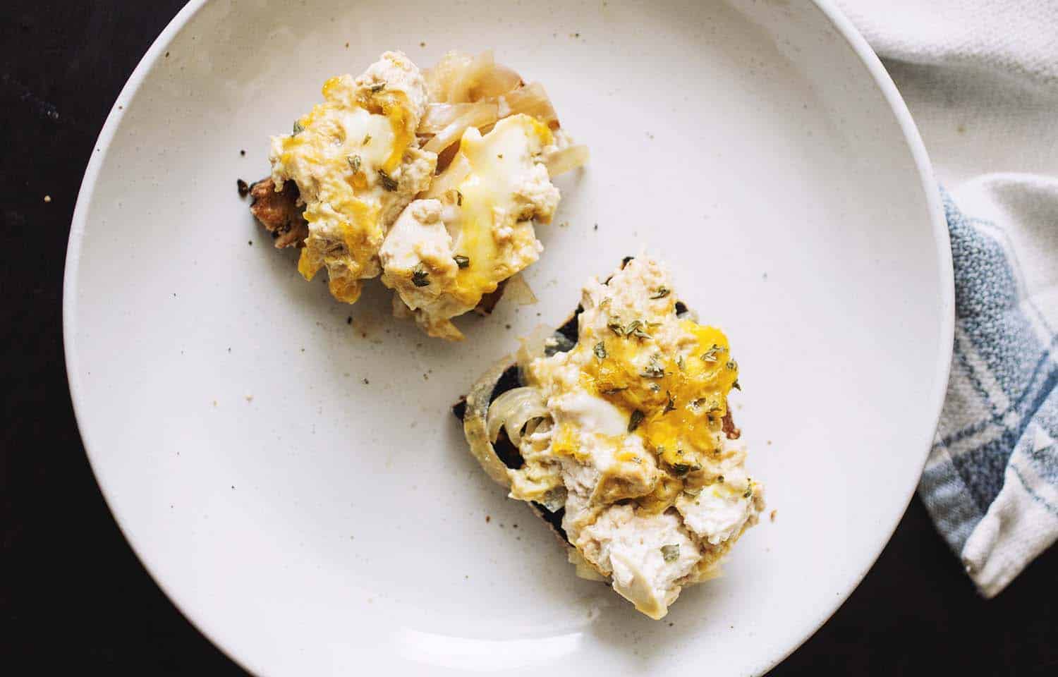 Two slices of bread topped with tofu oyakodon on a white plate.