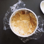 A gif of assembling a strawberry lemon milk bar-style cake with jam, cake, and crumbles.