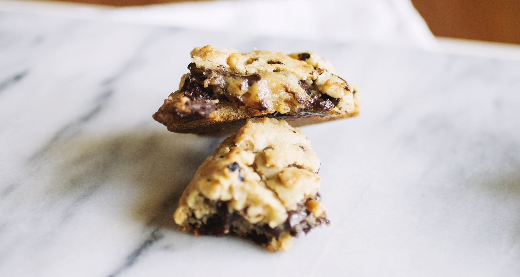 A chocolate chip Levain copycat cookie broken in half on a marble background.