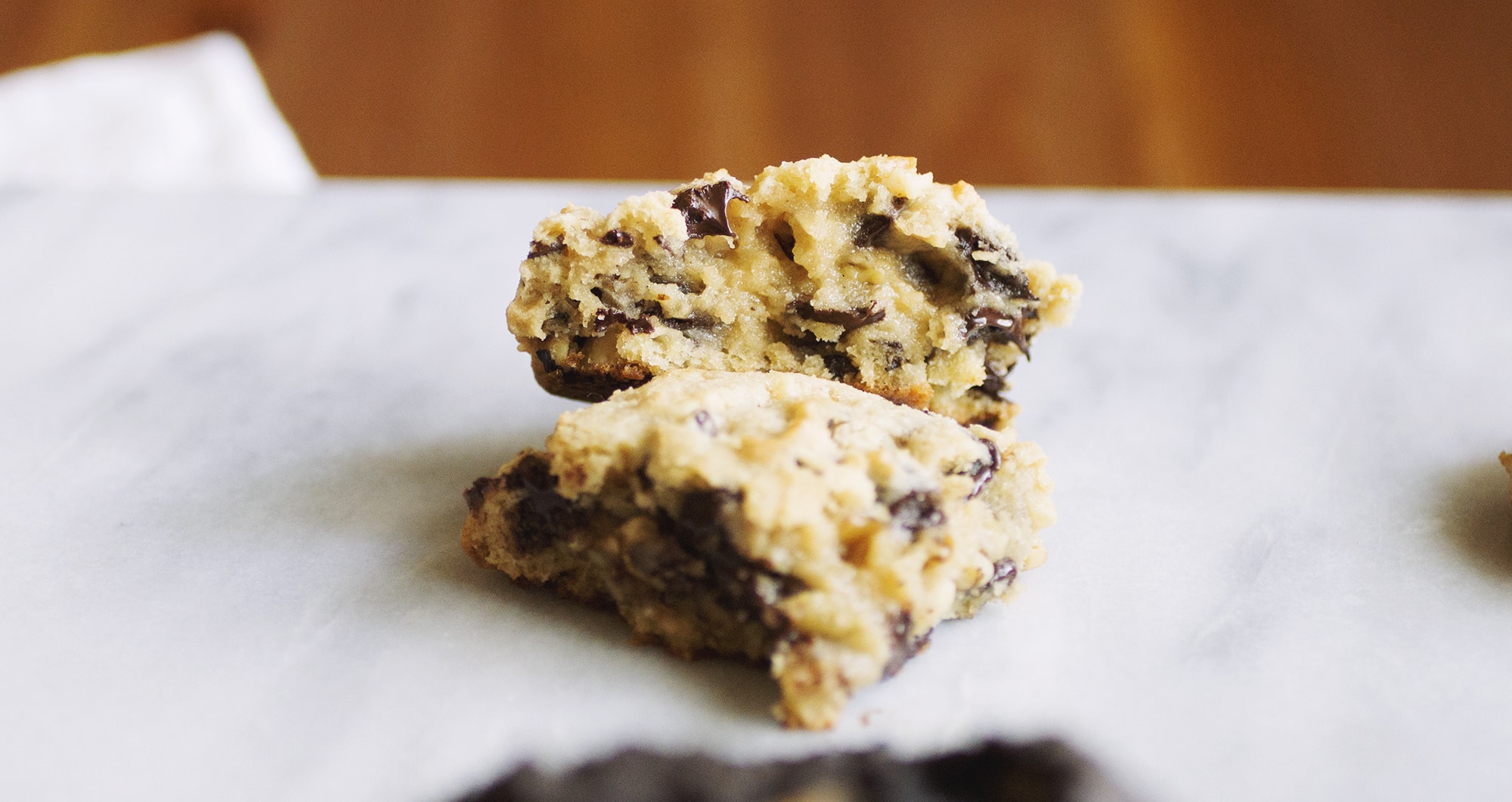 A chocolate chip Levain copycat cookie broken in half on a marble background.