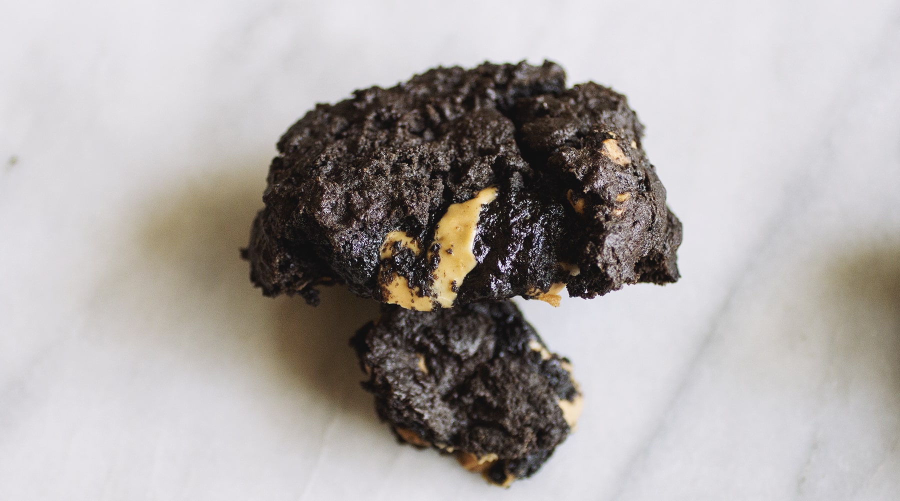 Half of a chocolate peanut butter Levain copycat cookie on a marble background.