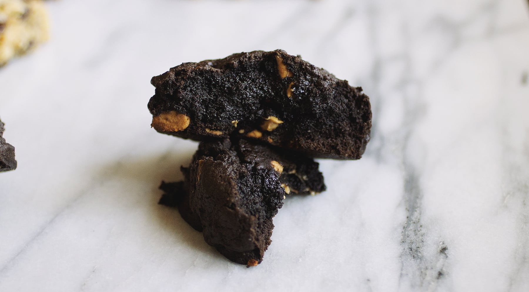 A chocolate peanut butter Levain copycat cookie broken in half on a marble background.