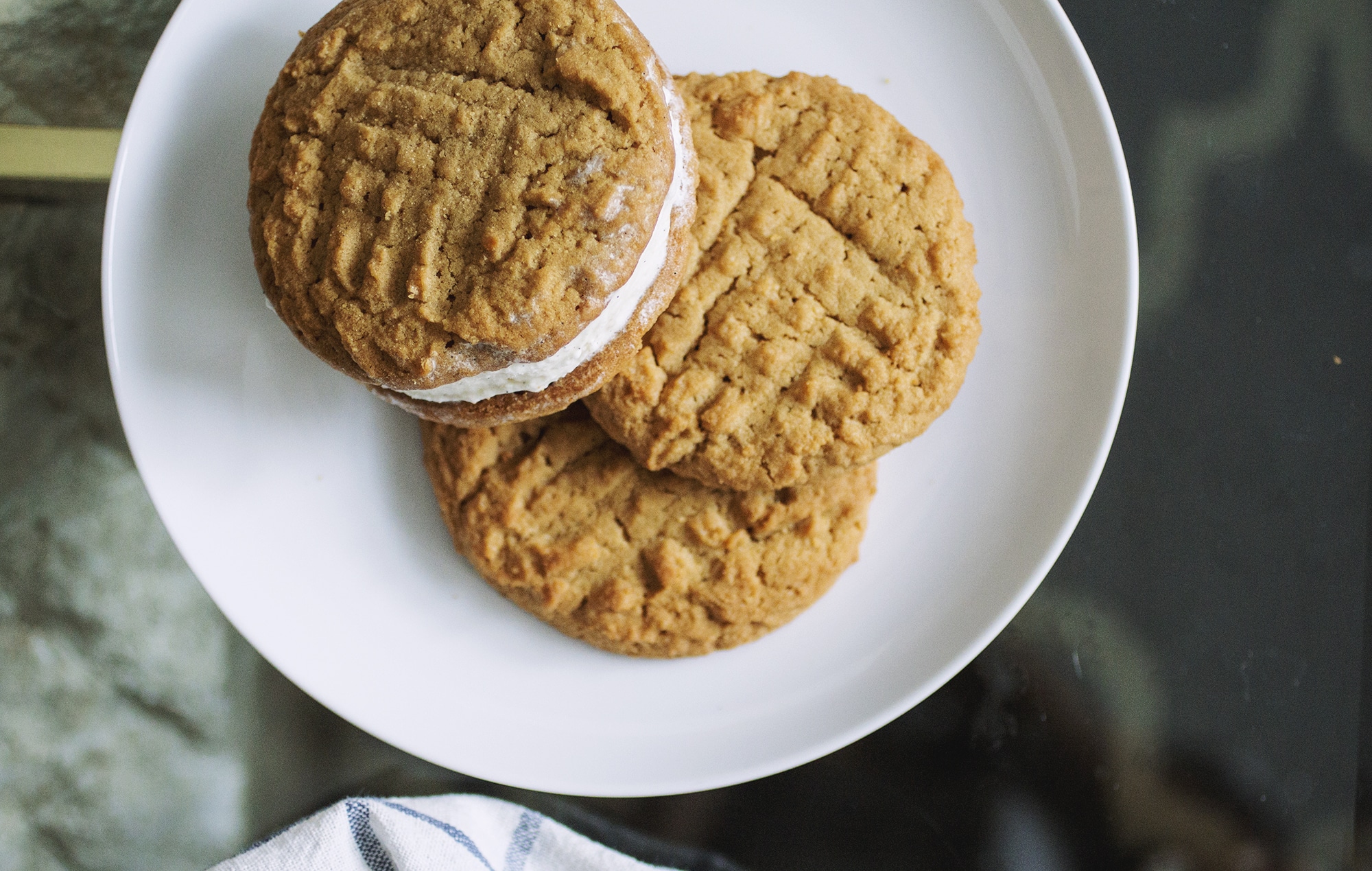A Wowbutter ice cream sandwich with two other cookies on a white plate.