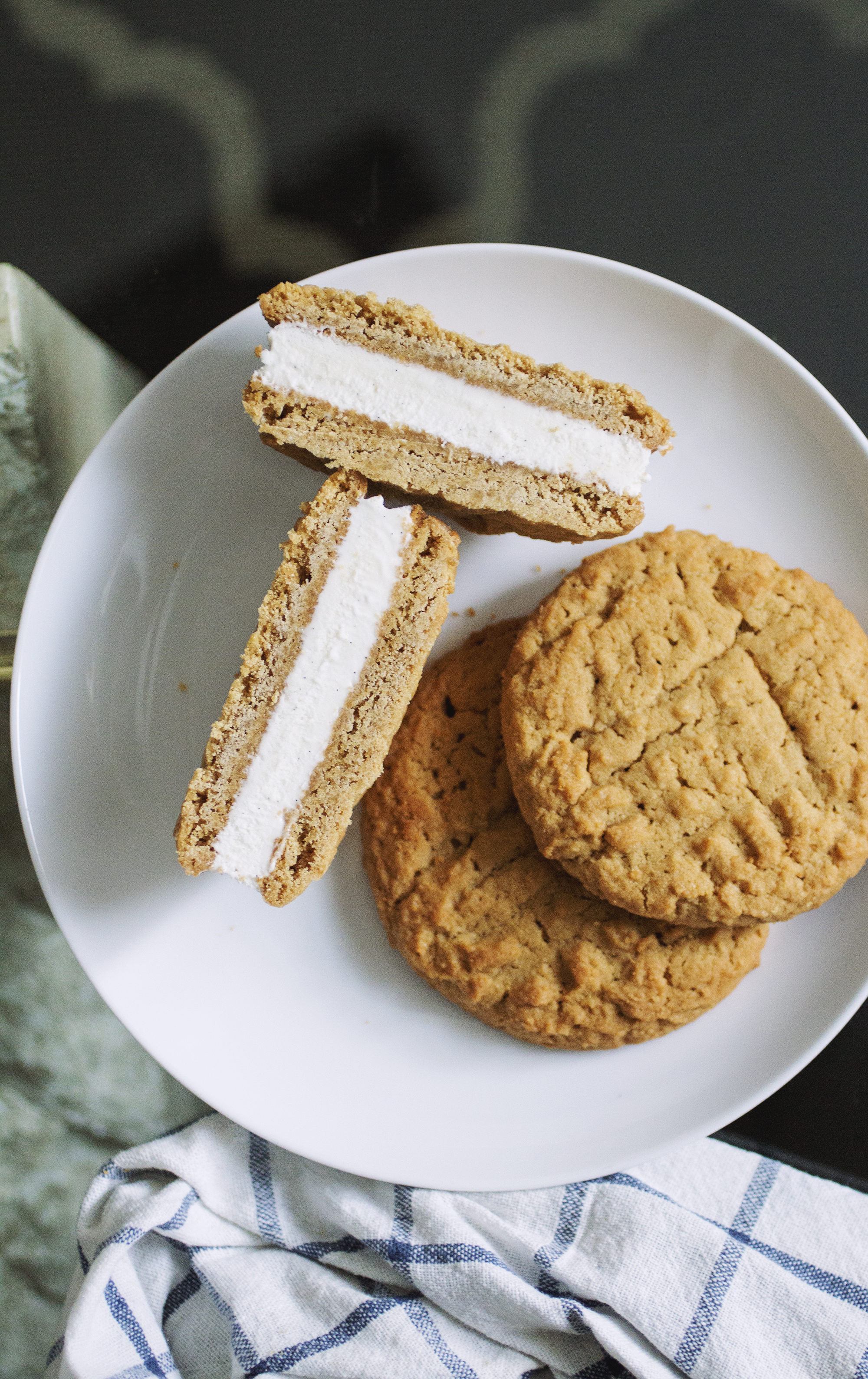 Two wowbutter cookies on a white plate with a halved wowbutter ice cream sandwich.