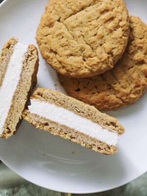 Two wowbutter cookies on a white plate with a halved wowbutter ice cream sandwich.