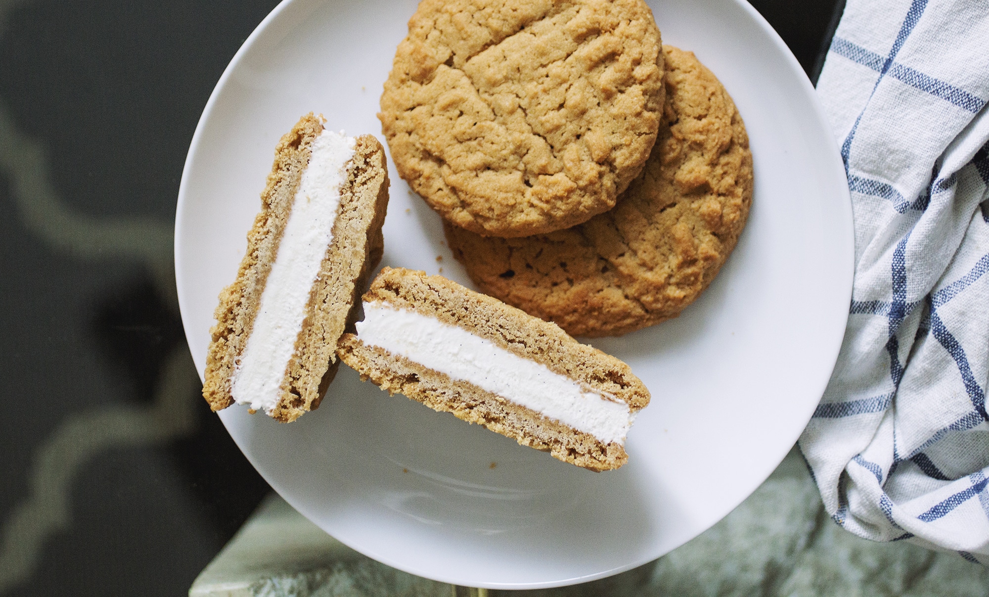 Two wowbutter cookies on a white plate with a halved wowbutter ice cream sandwich.
