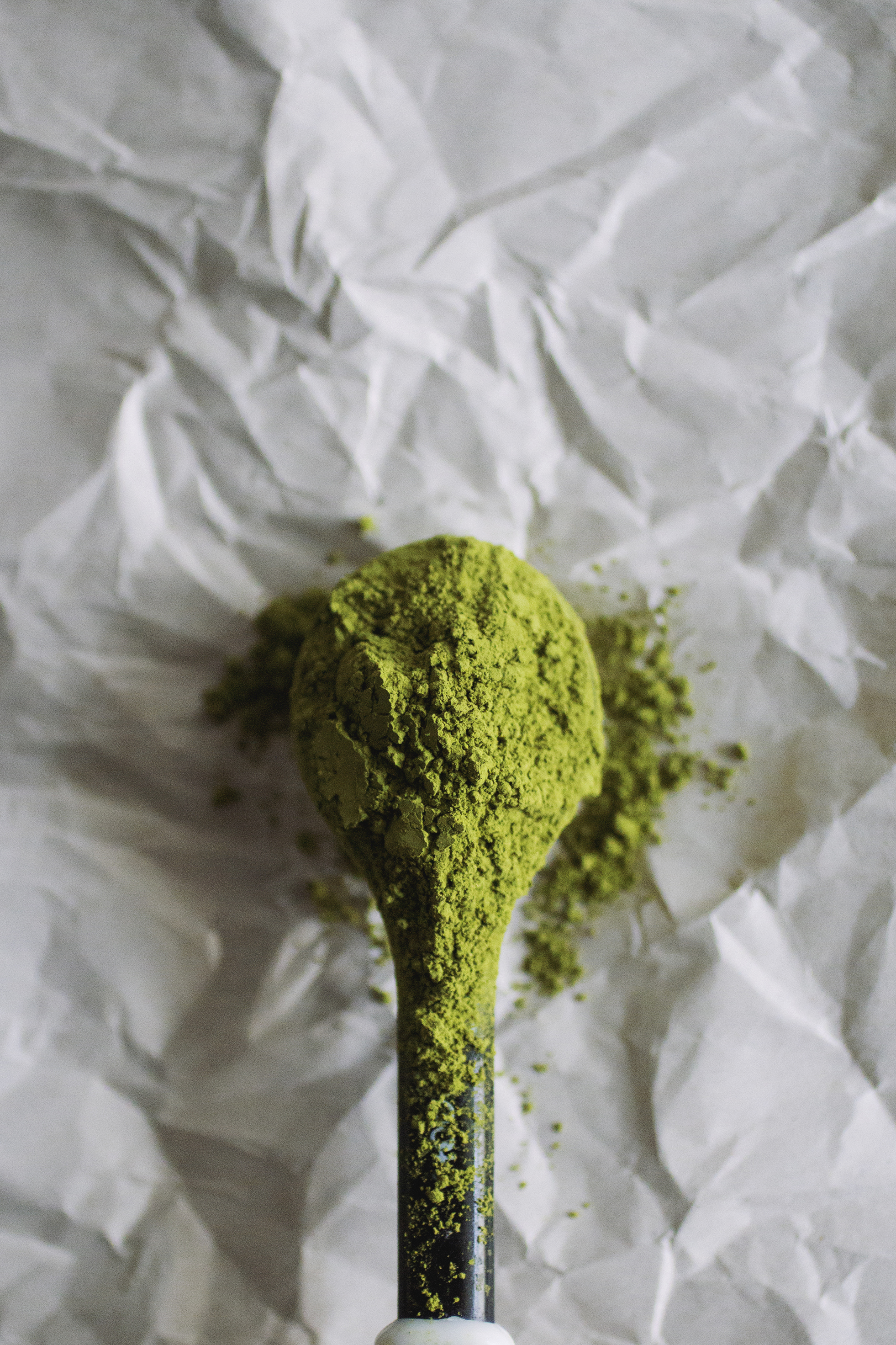 A teaspoon filled with matcha powder.