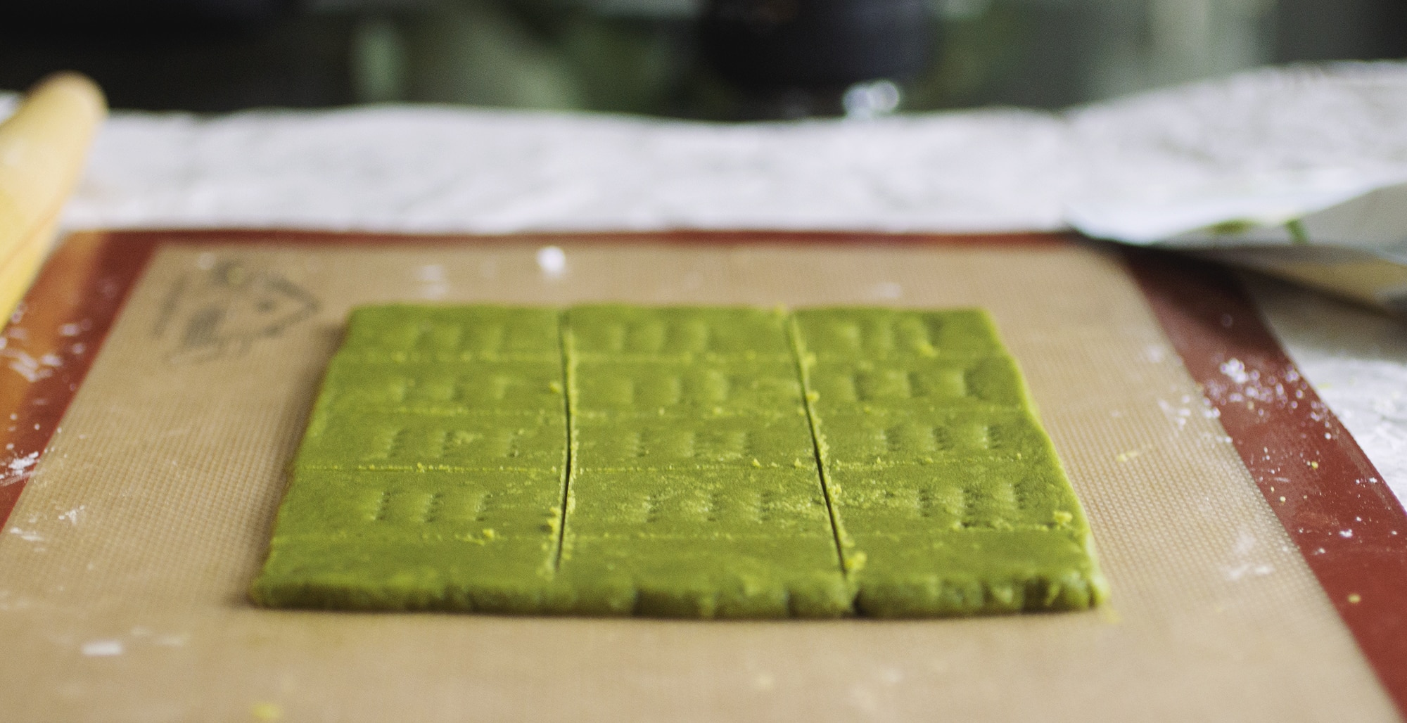 Matcha graham crackers cut out on a silpat mat.