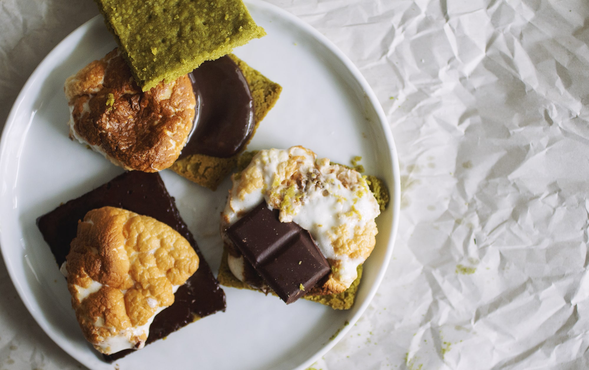 Three open-faced matcha s\'mores on a white plate.