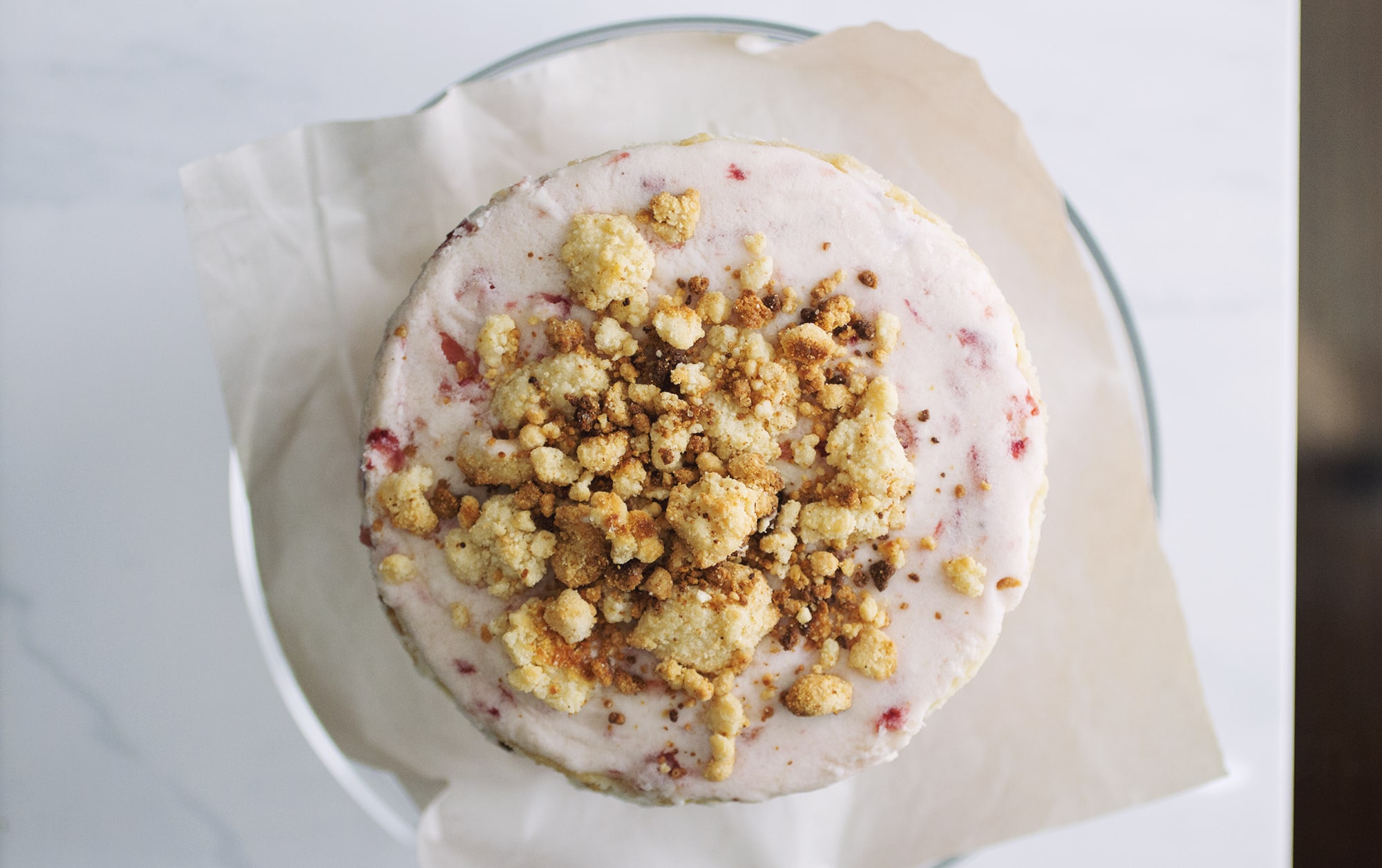 A triple layer strawberry cake with tons of milk crumbs on top.