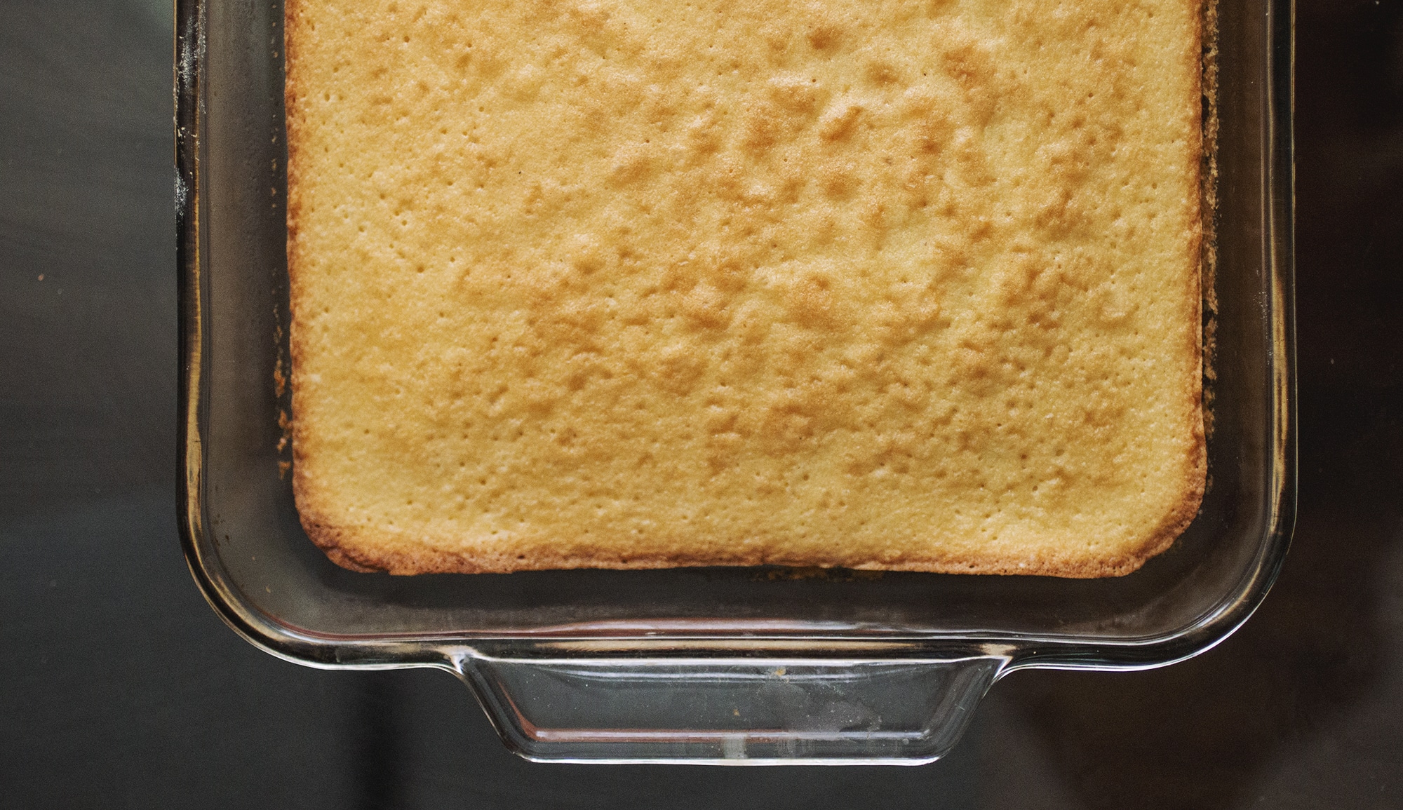 Baked vanilla cake in a glass pan.