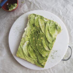 A matcha avocado toast cake on a white cutting board.