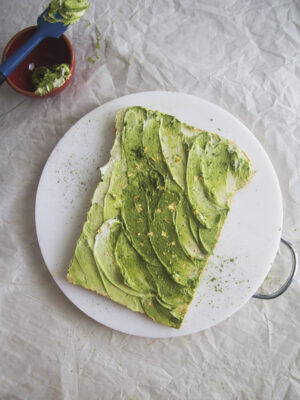 A matcha avocado toast cake on a white cutting board.