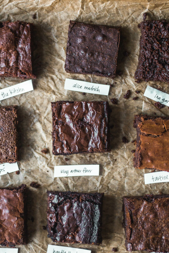 9 different squares of brownies on a sheet of parchment.