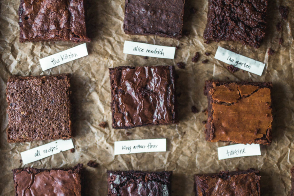 9 different squares of brownies on a sheet of parchment.